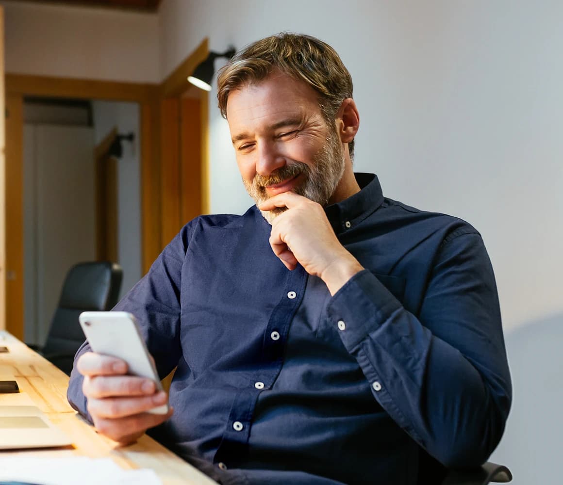 A man smiling while looking at his phone
